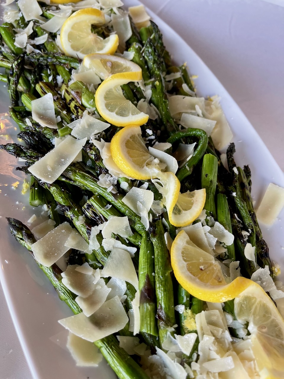 plate of asparagus with shaved parmesan and lemon slices